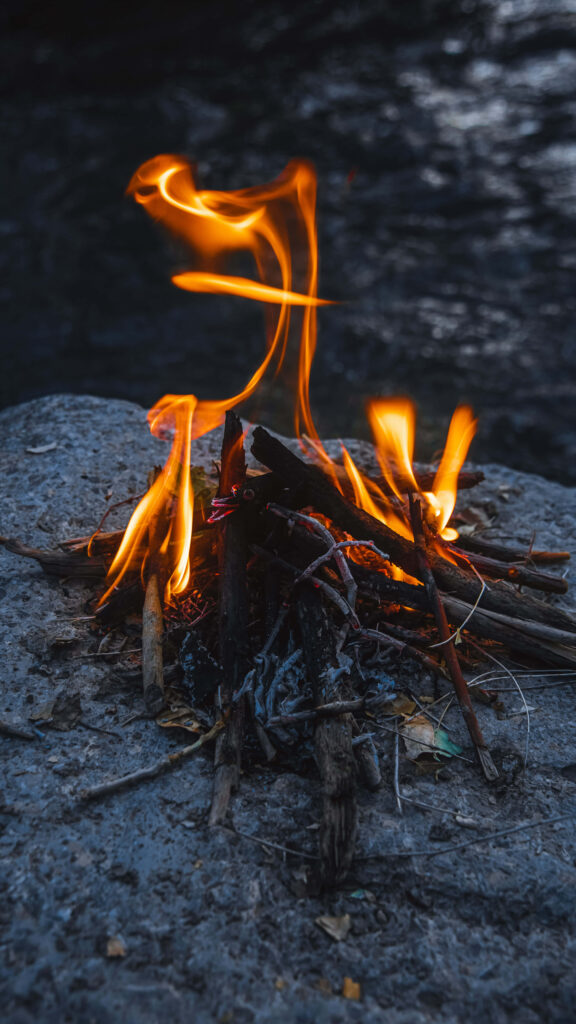 Close-up of blazing campfire flames on rugged stone surface warm rustic outdoor wallpaper background