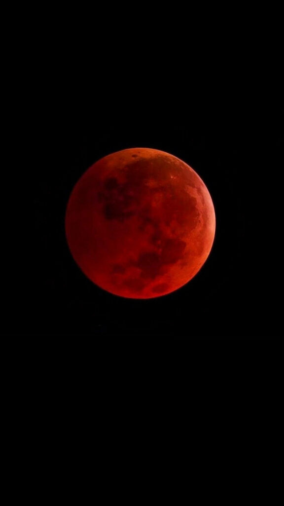 Fiery Crimson Moon on Black Background: Captivating Phone Wallpaper