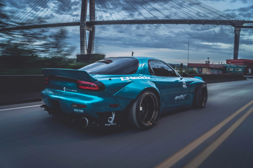 Aqua Blue Skyline: Capturing the Speed of an Rx-7 with the Dark & Cloudy Cityscape Wallpaper