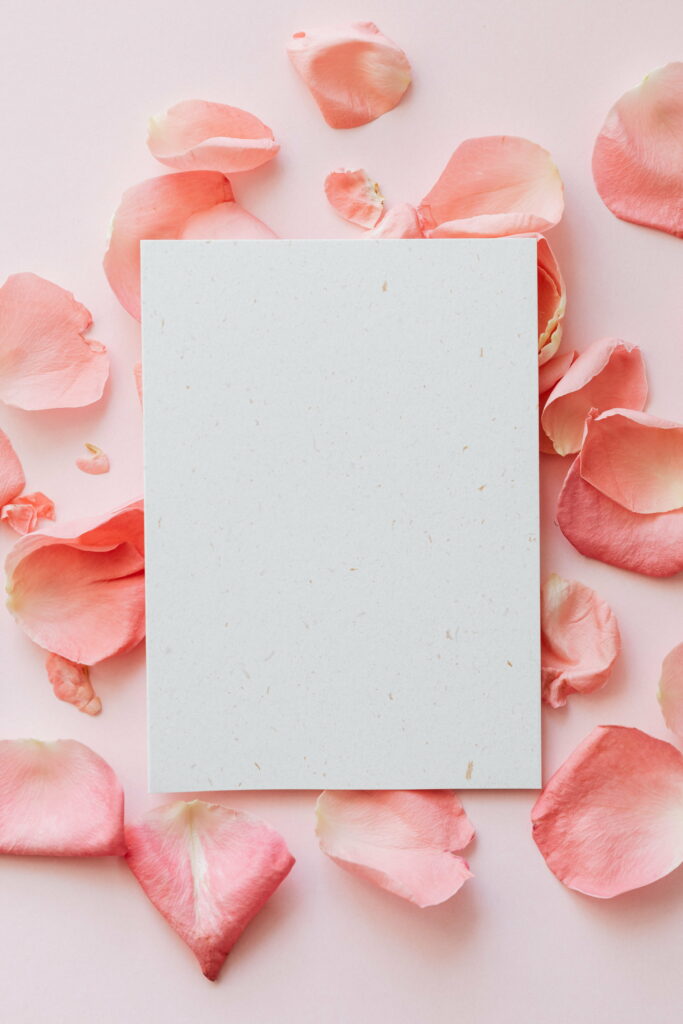Delicate Blooms and Whimsical Notes: Vibrant Floral Petals and Paper on a Blushing Backdrop Wallpaper