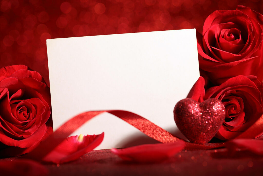 Romantic Love Expressed Through a Delicate Card Amidst a Gorgeous Red Rose Backdrop Wallpaper