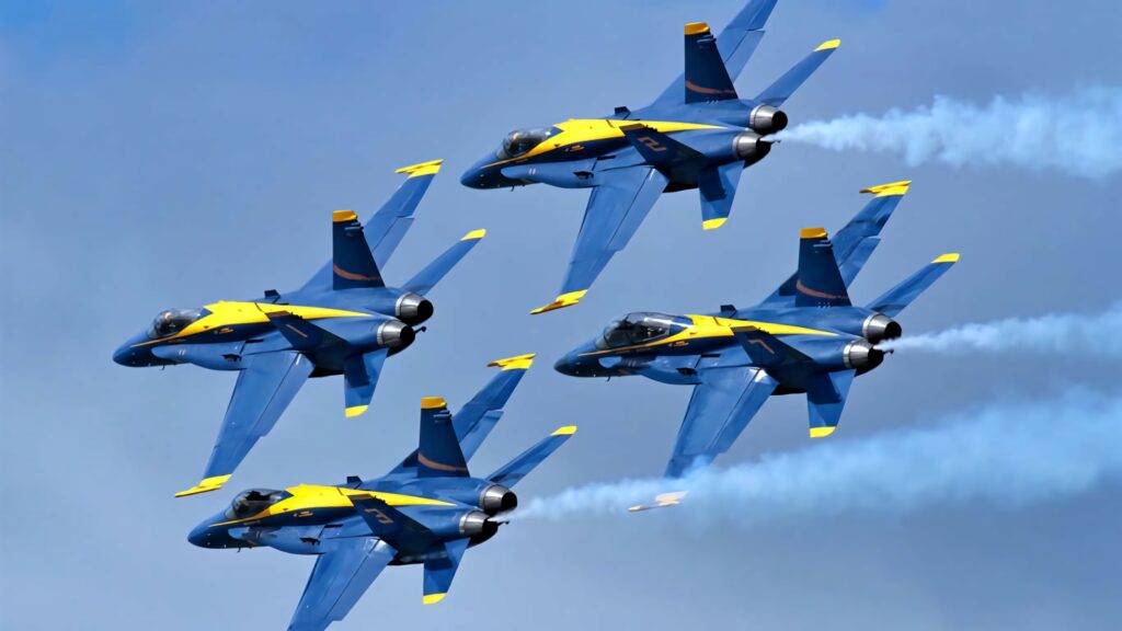 Four Blue Angels jets fly in tight formation with white trails against a clear blue sky background Wallpaper