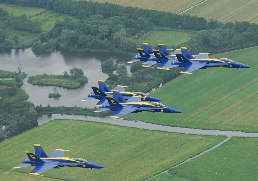 US Navy Blue Angels fly in tight formation over green fields and rivers vivid blue yellow jets Wallpaper