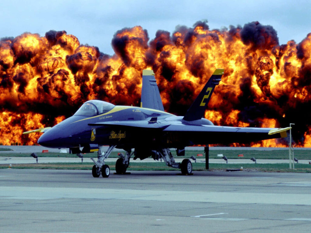 Blue Angels jet on runway with fiery explosions showcasing aerial precision and thrilling intensity Wallpaper