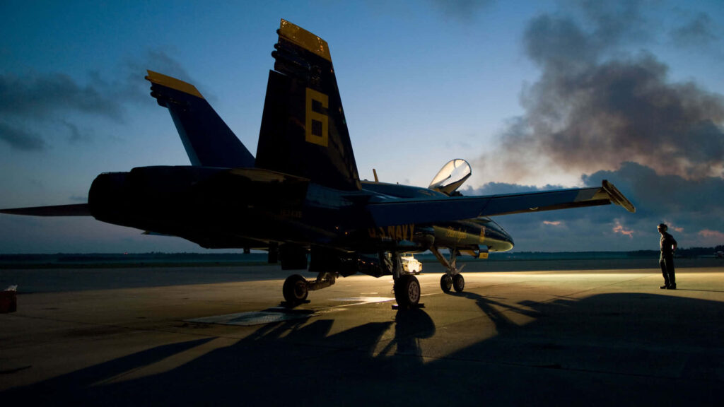 Silhouette of Blue Angels aircraft on runway at dusk with glowing clouds and deep blue skies Wallpaper