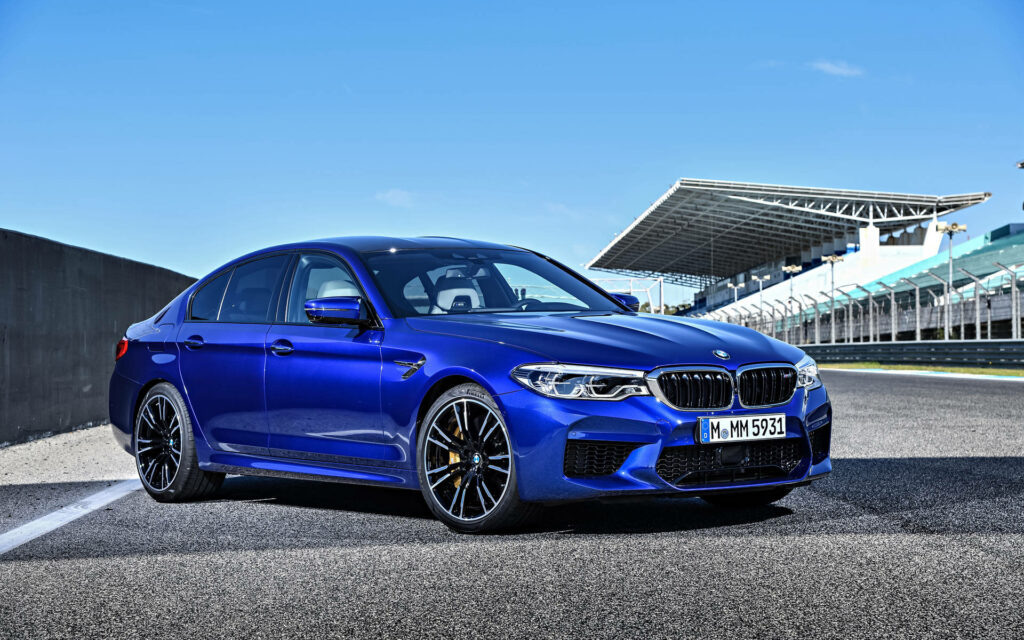 Blue BMW M5 parked on racetrack showcasing sporty design and power under clear sky Full HD Wallpaper