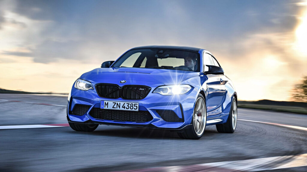 Blue BMW racing fast on curved track with dramatic sky high-performance car wallpaper background