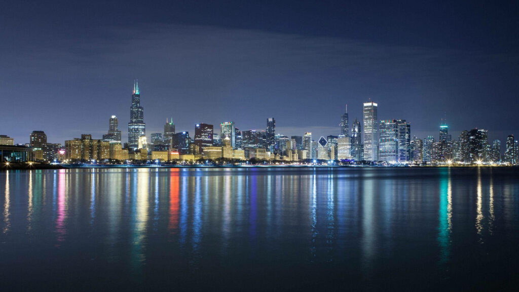 Blue Chicago skyline at evening with illuminated skyscrapers and reflections on Lake Michigan Wallpaper