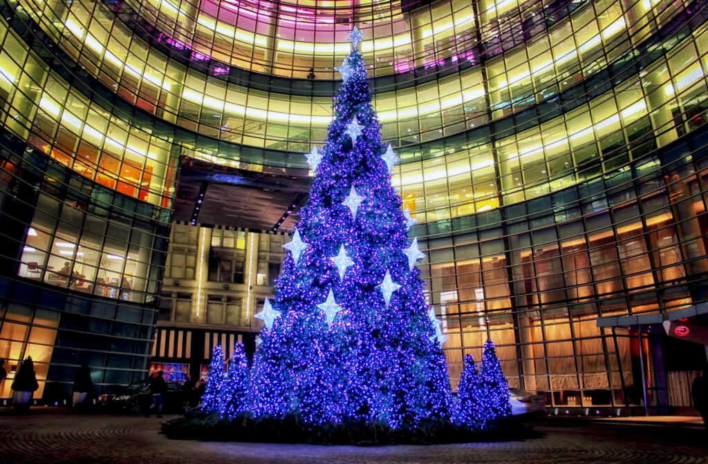 Blue-lit Christmas tree at Deutsche Bank Center against NYC curved glass urban skyline wallpaper