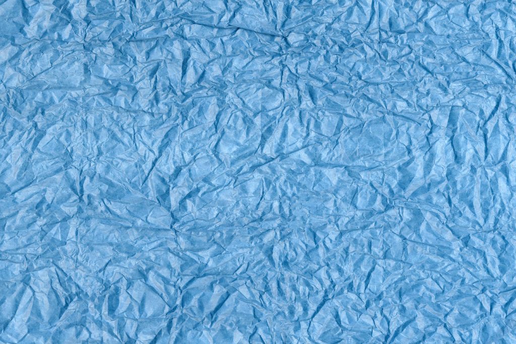 Striking blue crumpled paper wallpaper with textured creases and dramatic shadows background