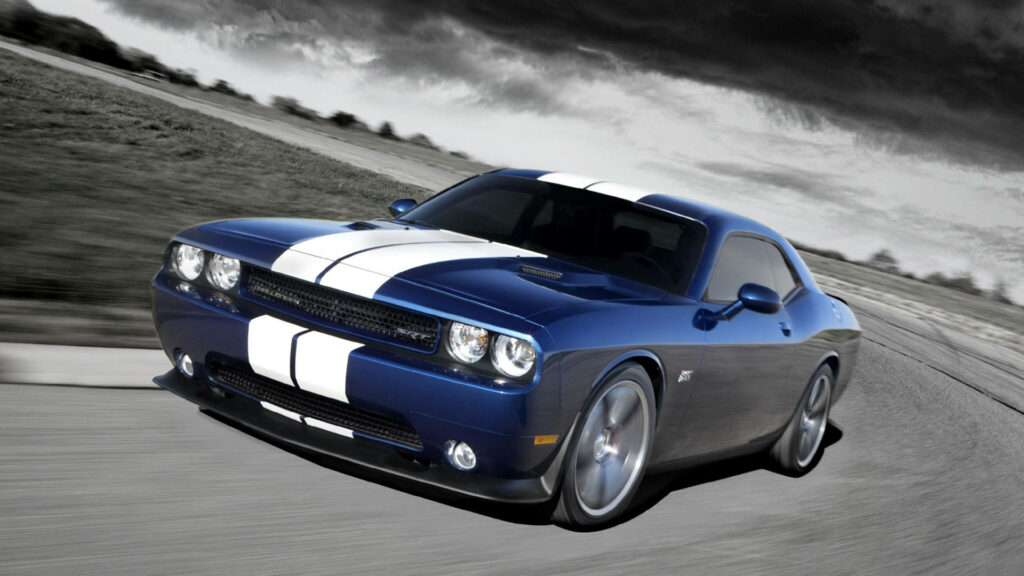 Blue Dodge Challenger with white racing stripes speeding on curving road under dark clouds Wallpaper
