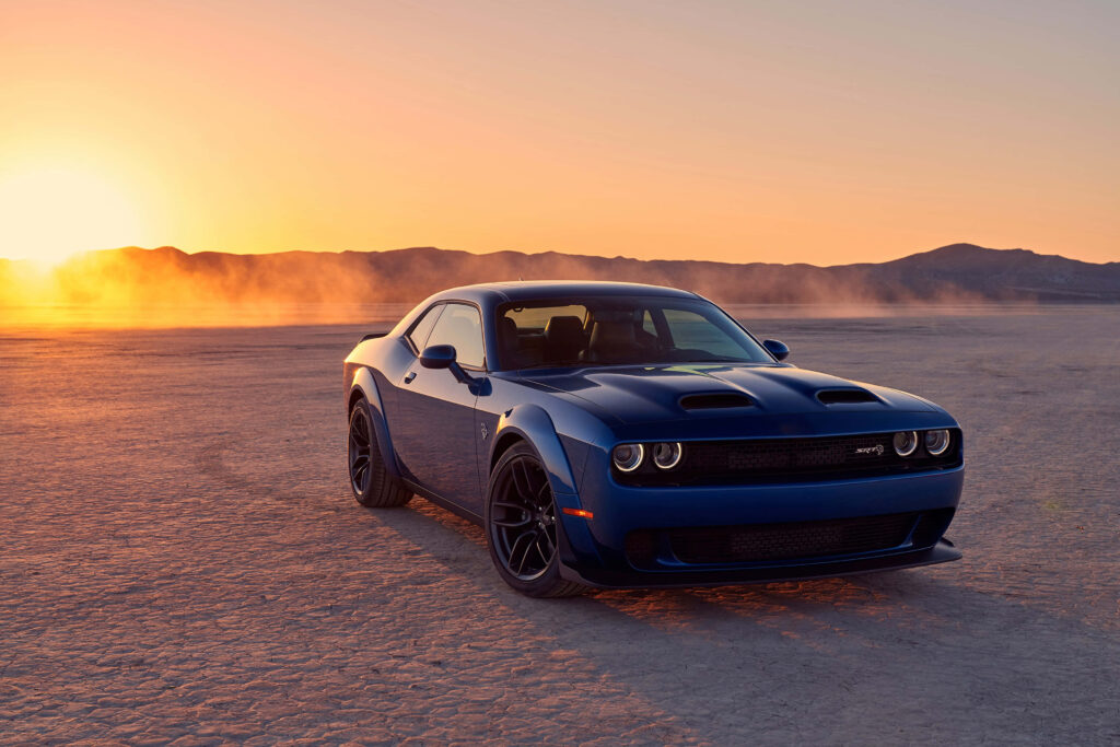 Blue Dodge Hellcat parked in desert at sunset with golden light and dramatic shadows in 4K wallpaper