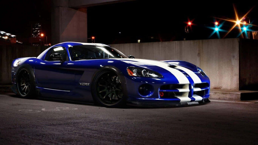 Blue Dodge Viper with white racing stripes under city lights at night high speed performance car Wallpaper