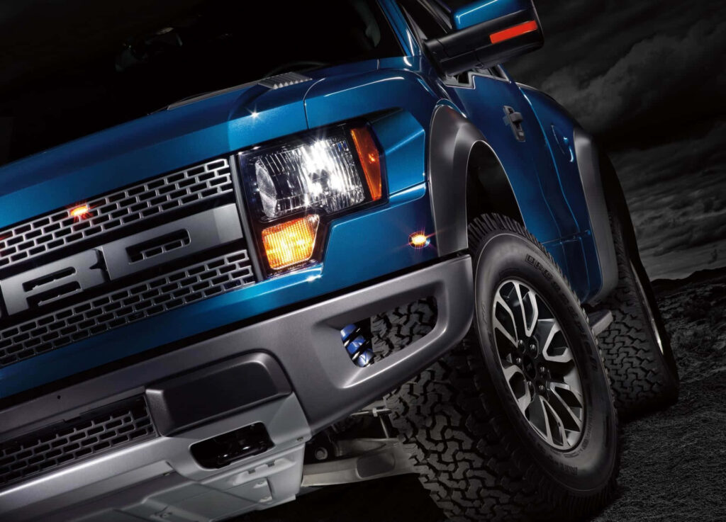 Blue Ford F-150 truck front view with rugged grille powerful headlights and durable tires outdoors Wallpaper