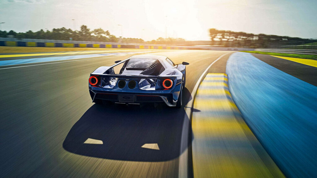 Blue Ford GT back view racing on sunlit track showcasing sleek design powerful sports car wallpaper