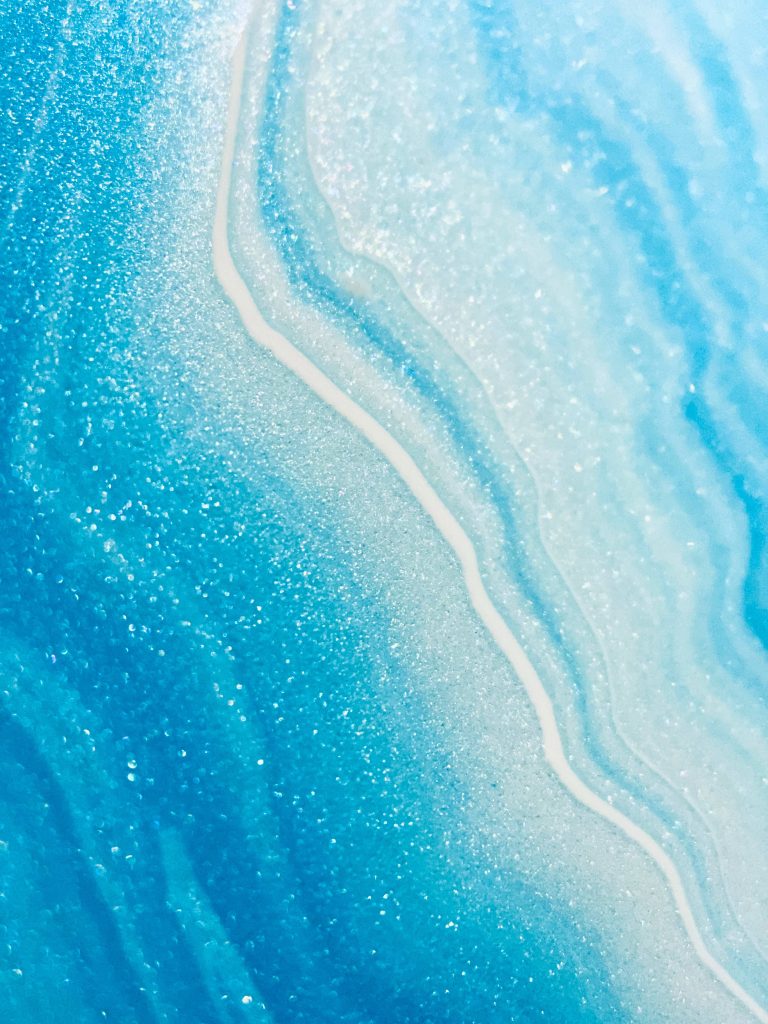 Blue glitter ocean abstract wallpaper with swirling blue and white agate texture and sparkle