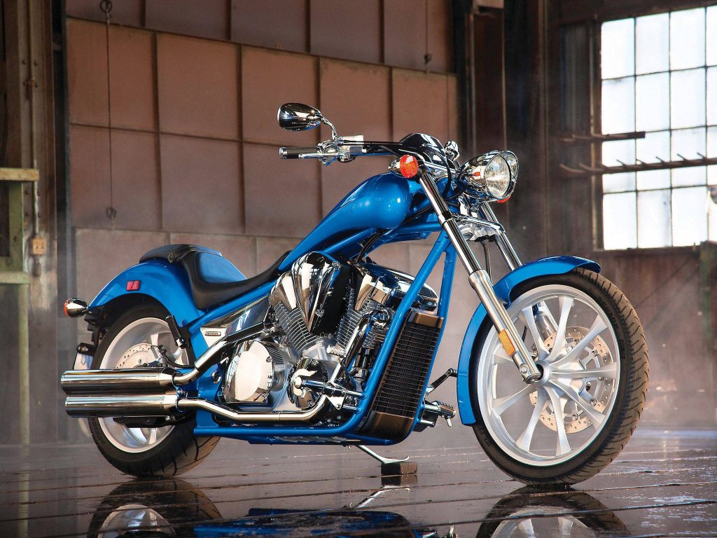 Blue Honda Fury cruiser motorcycle with chrome accents in industrial studio wallpaper background