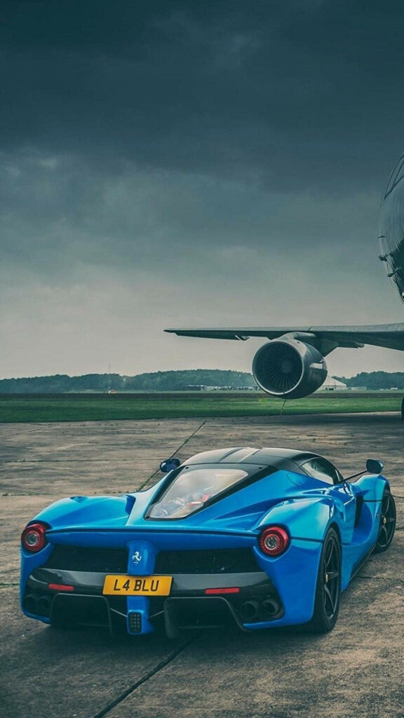 Blue La Ferrari parked on airport runway with jet engine and dramatic cloudy sky background Wallpaper