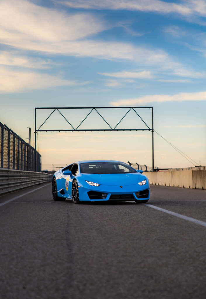 Blue Lamborghini on racetrack under clear sky showcasing speed luxury and stylish design wallpaper
