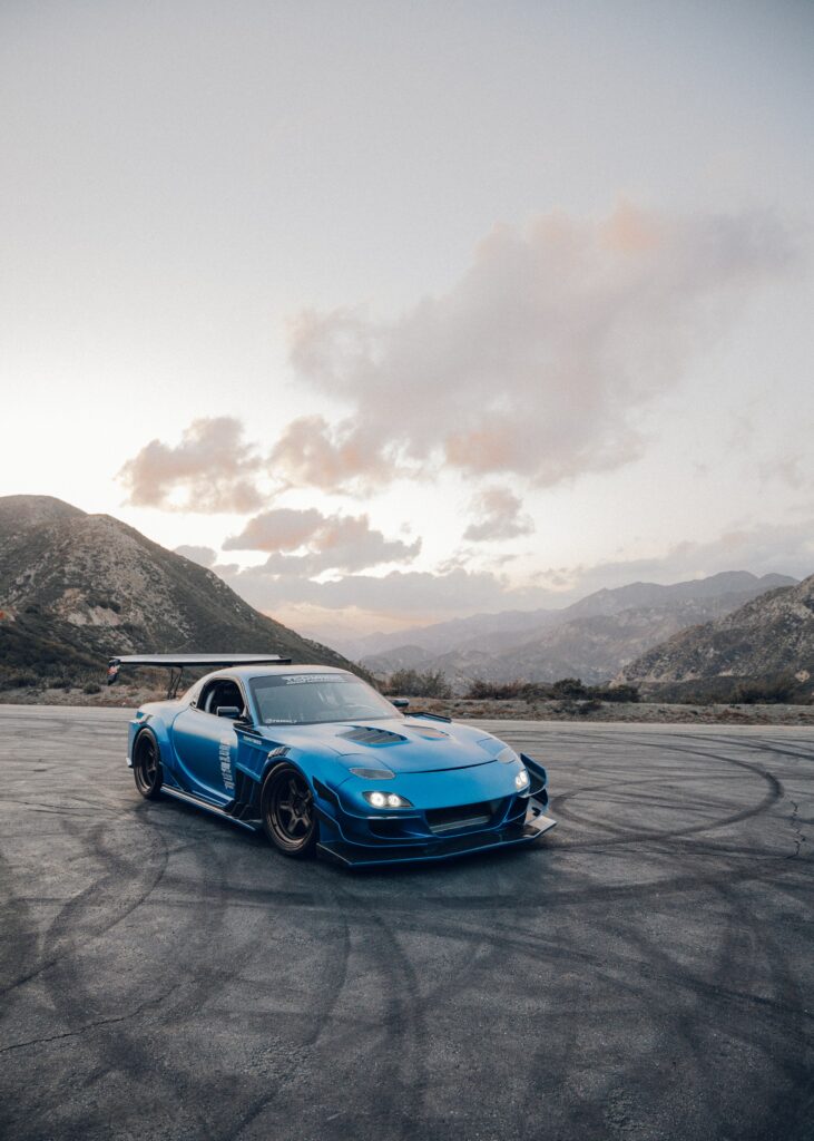 Stunning Blue Mazda RX-7 on Asphalt with Scenic Mountain Background Wallpaper