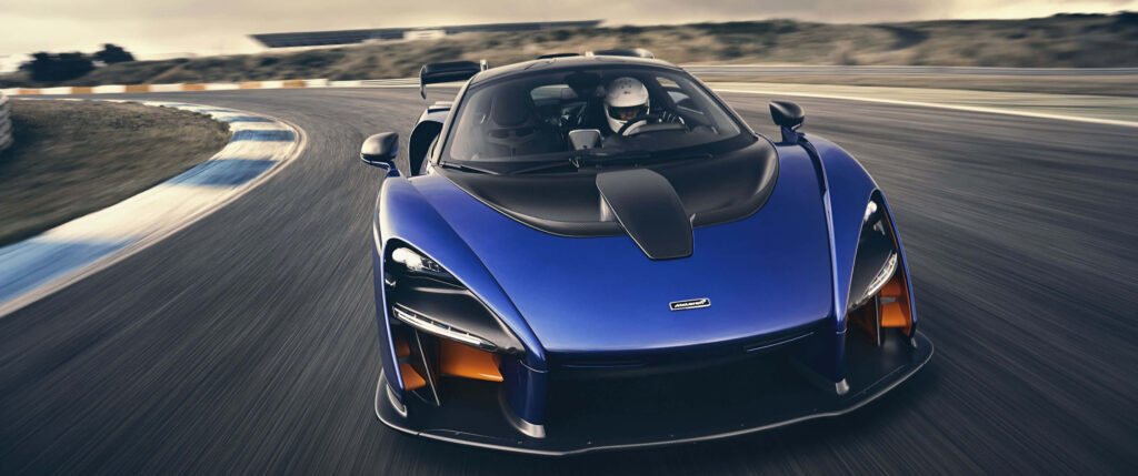 Blue McLaren Senna speeding on racetrack highlighting aggressive design and aerodynamics Wallpaper