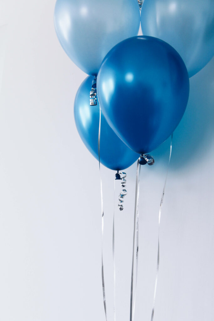 Cluster of blue metallic balloons with silver ribbons floating on white background festive wallpaper