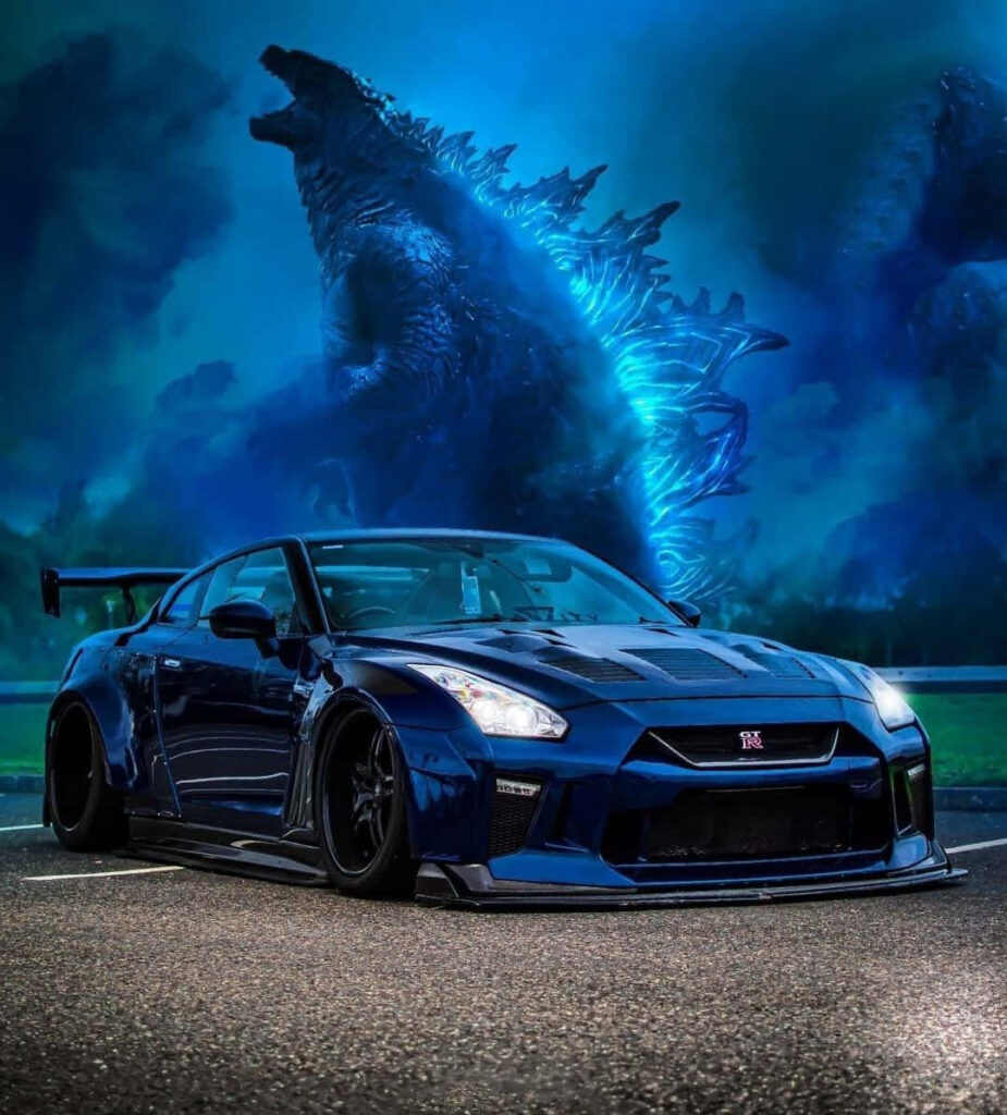 Blue Nissan R35 GTR on road with illuminated Godzilla in dramatic night sky wallpaper background