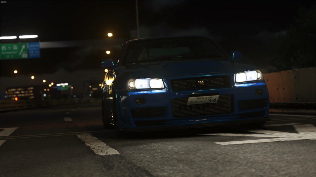 Blue Nissan Skyline GTR R34 front view on dimly lit highway at night city lights wallpaper background