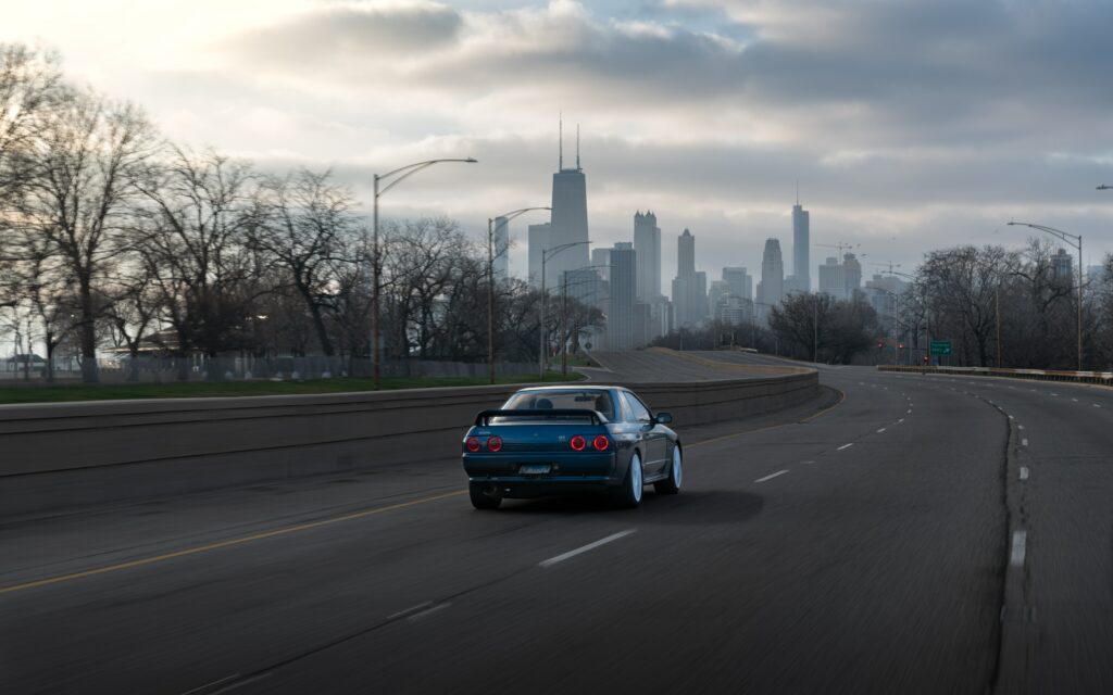 Blue Nissan Skyline R32 Racing Through Urban Cityscape Wallpaper