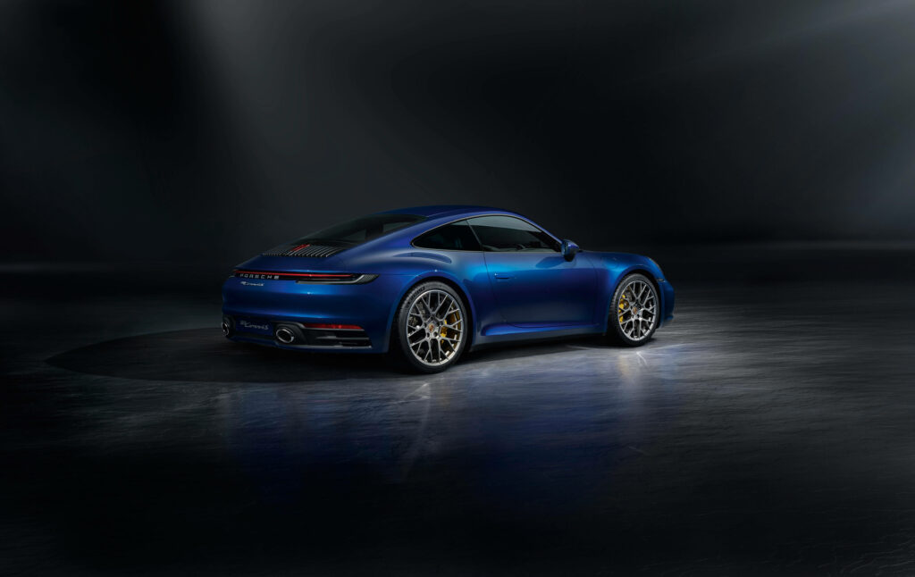 Blue Porsche sports car with sleek curves under dramatic lighting on dark minimalist background Wallpaper