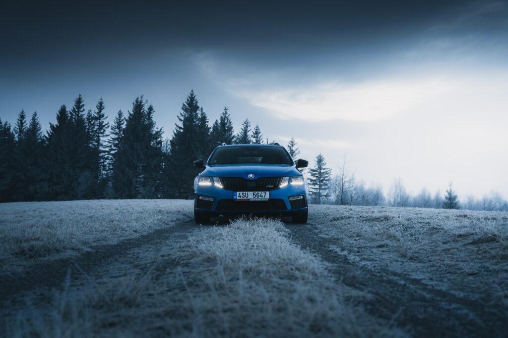 Blue Škoda Car on Frosty Road: Serene Winter Forest Background Wallpaper
