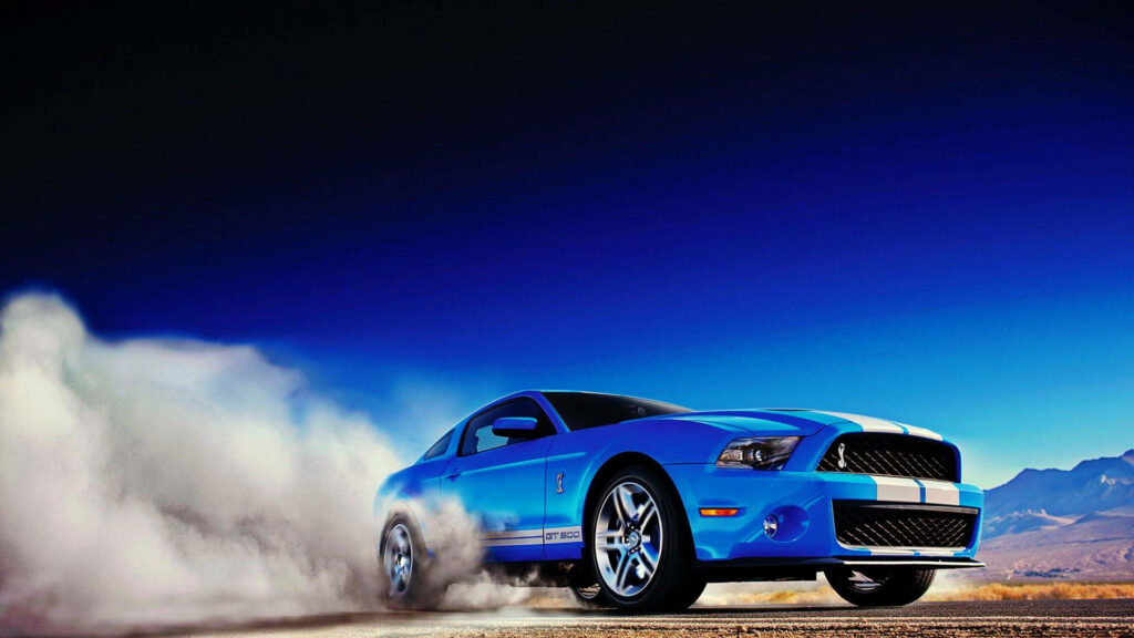 Blue sports car racing through desert kicking up dust under clear deep blue sky wallpaper background