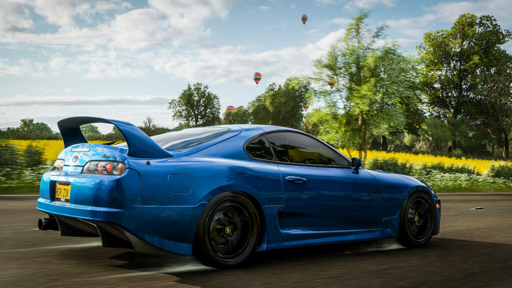 Blue sports car racing on scenic countryside road in Forza 4 video game wallpaper background