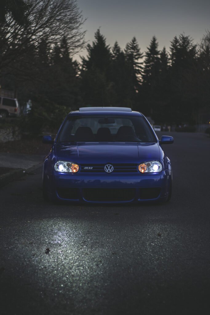 Blue Volkswagen Golf at Night: Illuminated on Dimly Lit Road Wallpaper