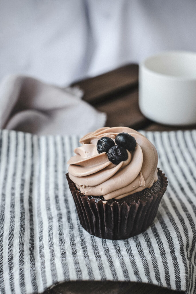 Blueberry chocolate cupcake with rich frosting on striped cloth cozy artisanal dessert wallpaper