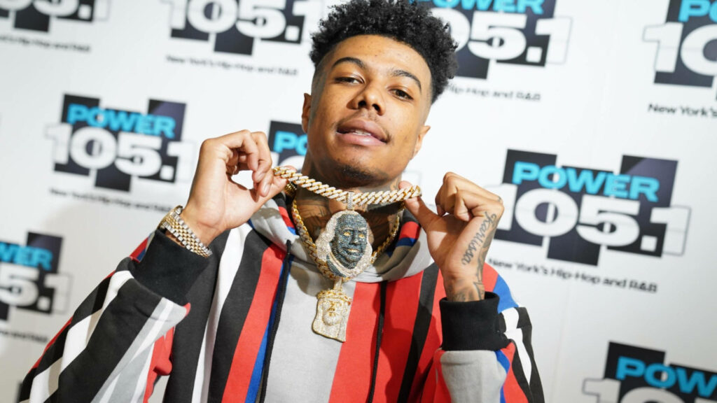 Blueface wearing diamond Ben Franklin pendant posing in front of Power 105 1 backdrop with bold style Wallpaper