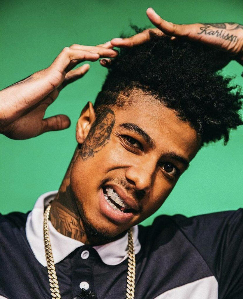 Blueface posing confidently with flashy jewelry and tattoos against vibrant green background wallpaper