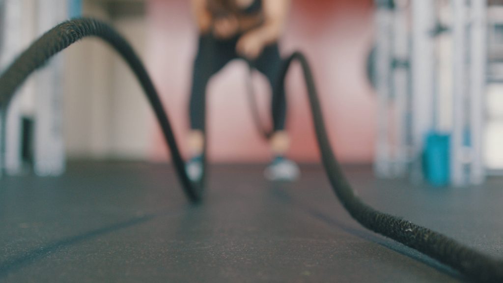 Blurred gym background with sharp battle ropes foreground highlighting intense interval training Wallpaper