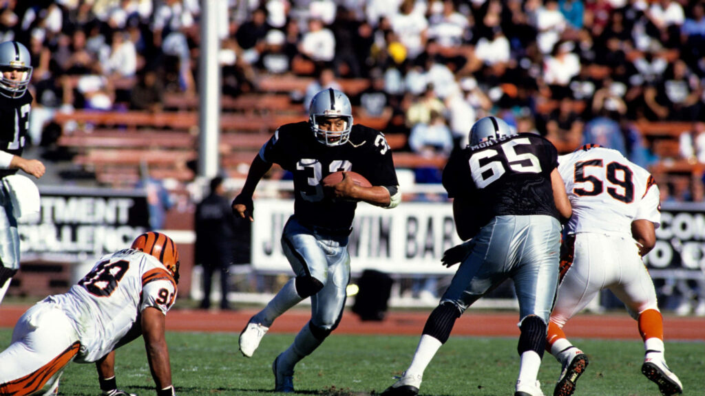 Bo Jackson in Raiders uniform breaks tackle against Bengals player intense football action wallpaper