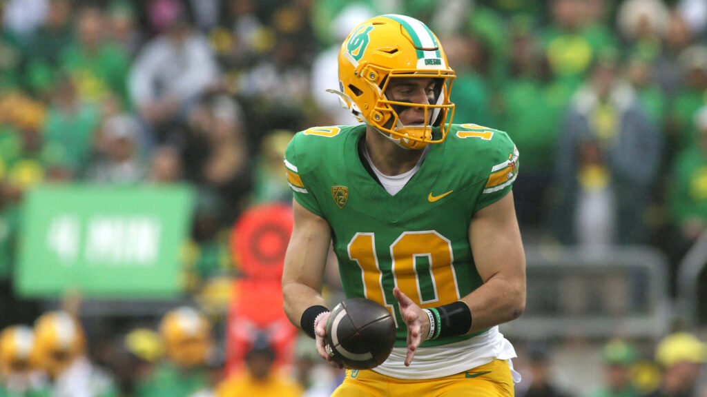 Bo Nix in green yellow Oregon Ducks uniform poised to throw pass during intense football game Wallpaper