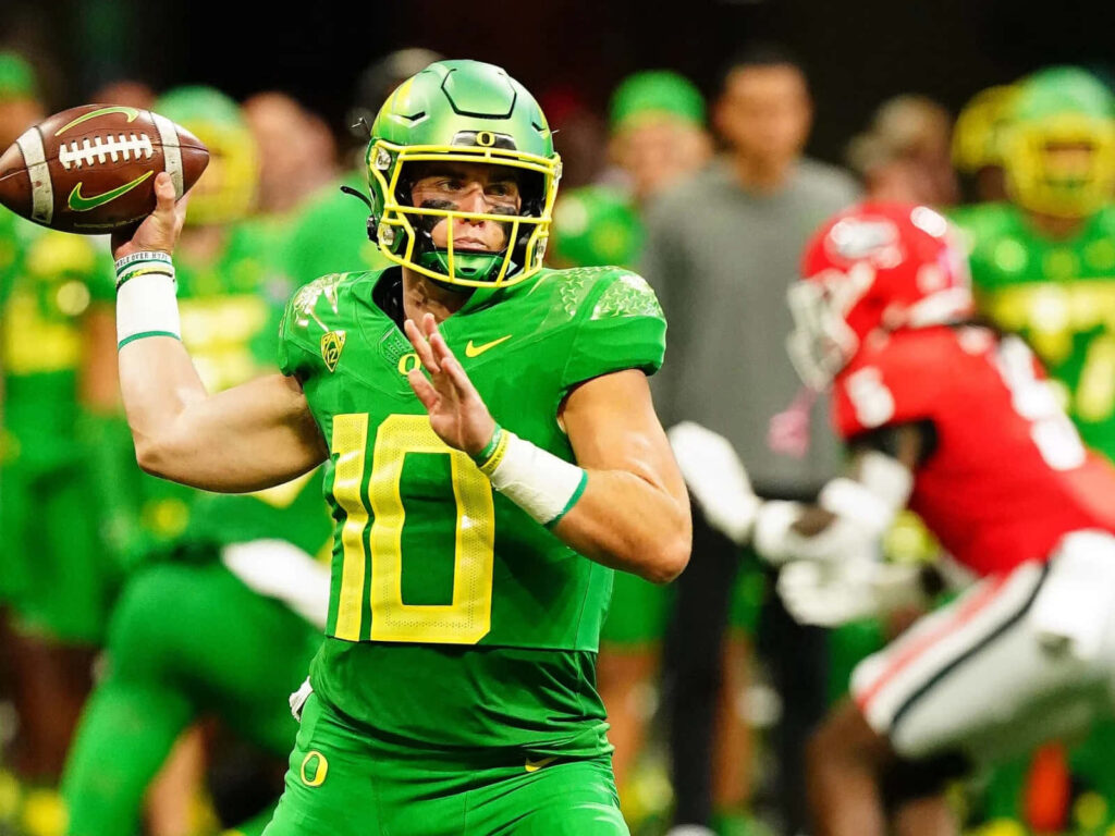Bo Nix in green Oregon Ducks uniform gearing up to throw football in intense game action wallpaper