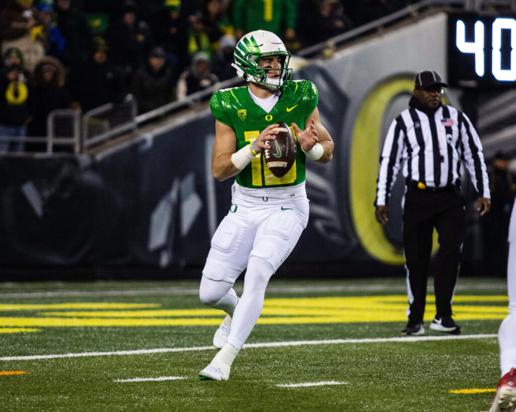 Oregon quarterback Bo Nix focused mid-play preparing to pass in intense football game wallpaper