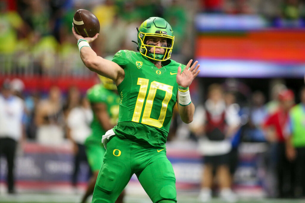 Bo Nix Oregon quarterback throwing football mid-action dynamic sports wallpaper background