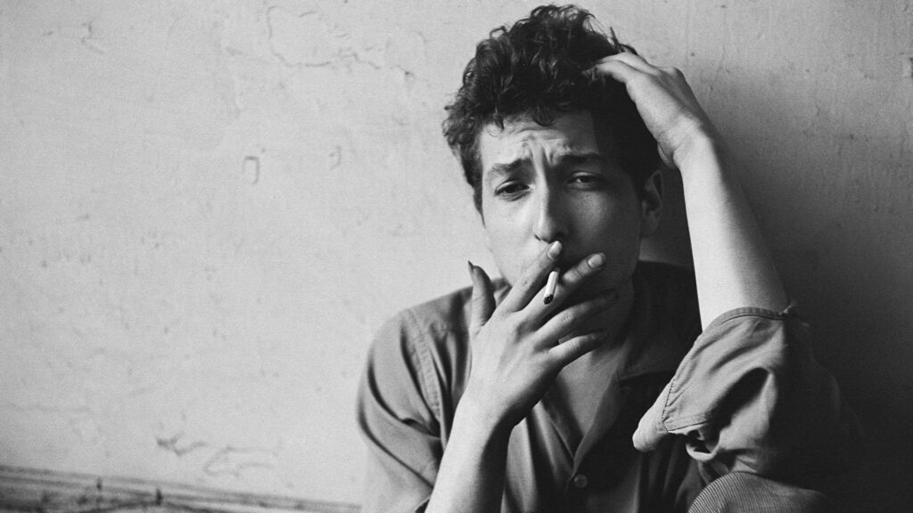 Striking greyscale portrait of Bob Dylan smoking against textured wall by John Cohen wallpaper