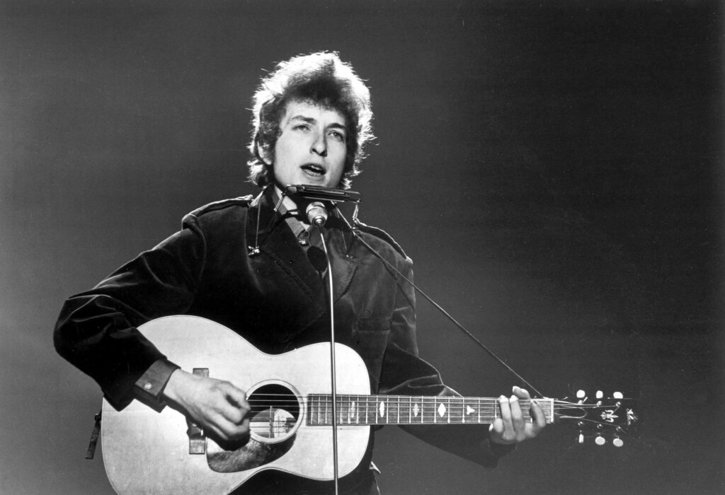 Bob Dylan playing guitar and harmonica black and white iconic music legend performance wallpaper