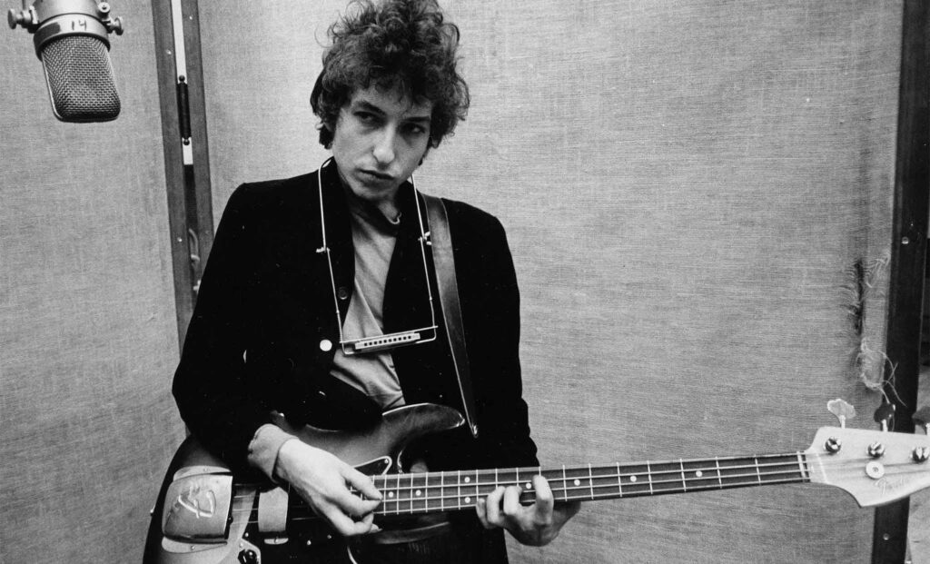 Bob Dylan playing guitar in a music studio capturing classic creative musical expression wallpaper