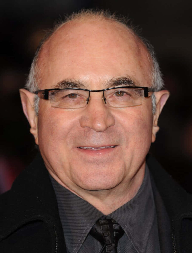 Portrait of Bob Hoskins in formal attire with warm expression wallpaper background