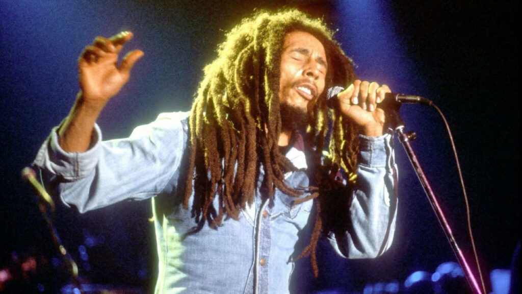 Bob Marley performing live with dreadlocks vibrant stage lights iconic reggae lead vocalist wallpaper