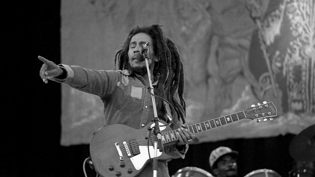 Bob Marley passionately performing live with guitar reggae icon wallpaper background image