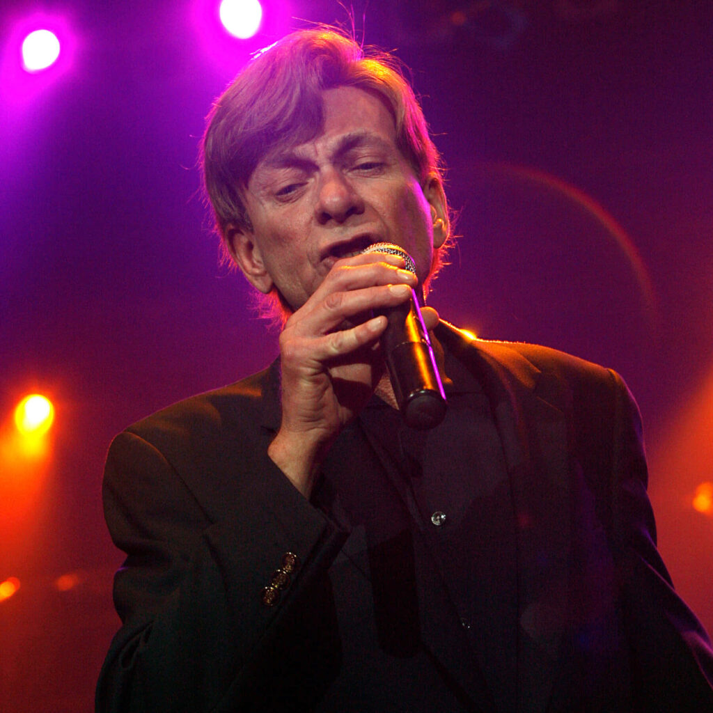 Bobby Caldwell soulful live performance on stage with vibrant colorful lighting background wallpaper